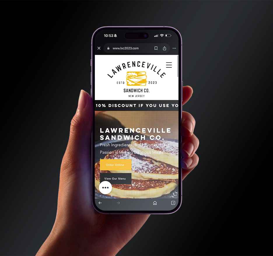A picture of a person holding up a phone with the Lawrenceville Sandwich Co. website on the screen.
